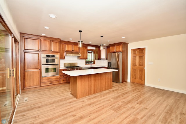 kitchen with pendant lighting, a kitchen island, stainless steel appliances, and light hardwood / wood-style flooring