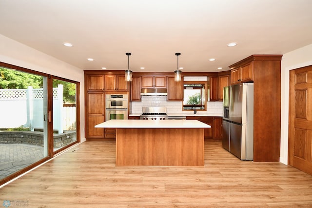 kitchen with appliances with stainless steel finishes, decorative backsplash, light hardwood / wood-style floors, a kitchen island, and pendant lighting