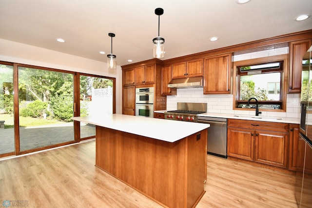 kitchen featuring pendant lighting, sink, stainless steel appliances, a center island, and light hardwood / wood-style floors