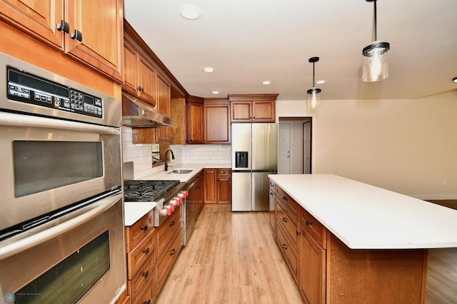 kitchen featuring light hardwood / wood-style floors, sink, a kitchen island, stainless steel appliances, and decorative light fixtures