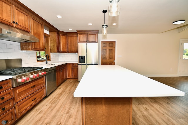 kitchen featuring light wood-type flooring, a center island, tasteful backsplash, hanging light fixtures, and appliances with stainless steel finishes