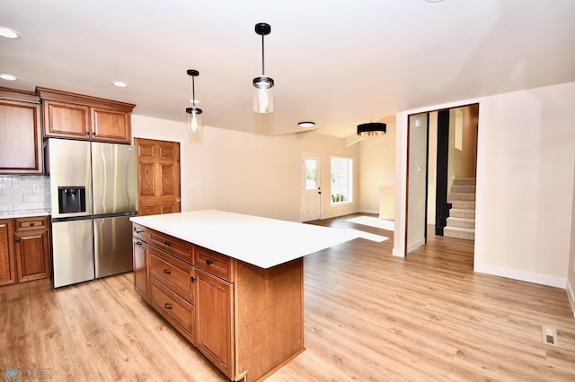 kitchen with a kitchen island, light hardwood / wood-style flooring, decorative light fixtures, stainless steel refrigerator with ice dispenser, and decorative backsplash