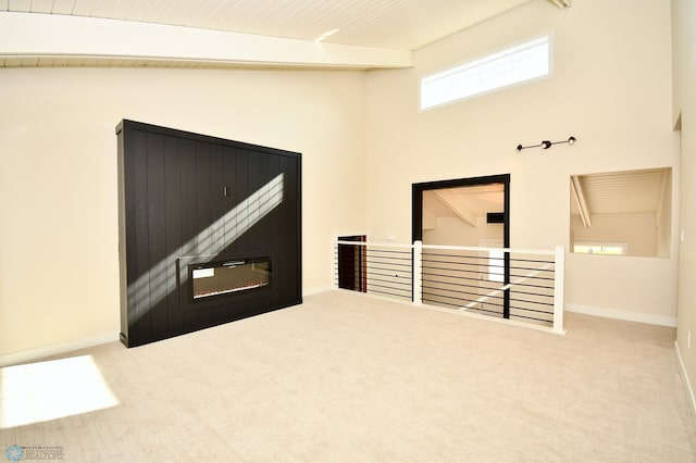 empty room featuring lofted ceiling with beams, wood ceiling, and light colored carpet