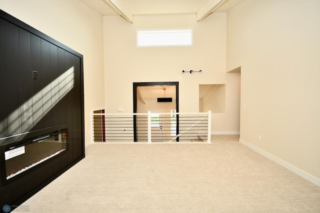 interior space with carpet floors, beam ceiling, and a towering ceiling