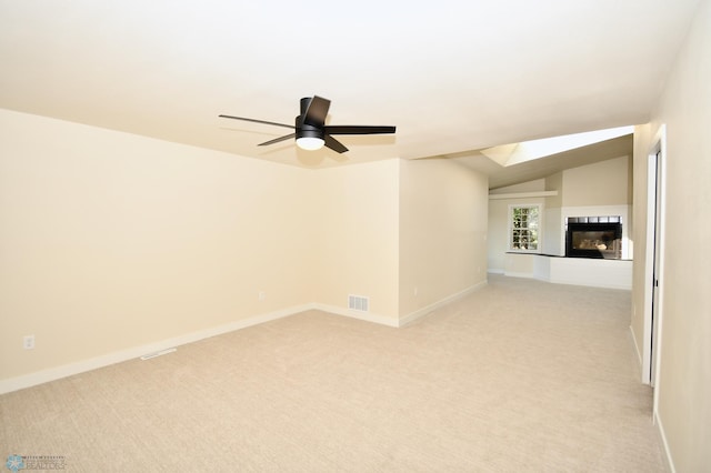 unfurnished living room featuring vaulted ceiling, ceiling fan, light colored carpet, and a fireplace