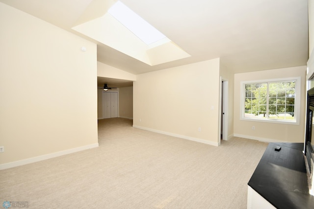 interior space featuring vaulted ceiling with skylight and light colored carpet