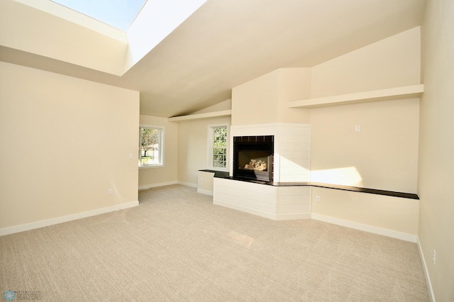 unfurnished living room with light carpet, vaulted ceiling with skylight, and a multi sided fireplace