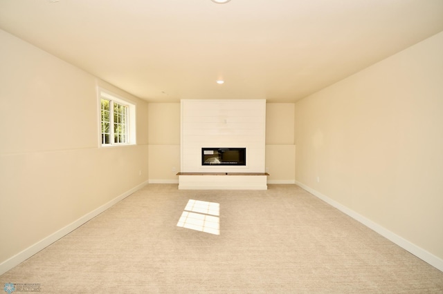 unfurnished living room featuring light carpet and a large fireplace