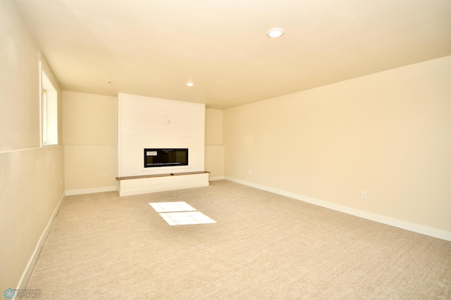 unfurnished living room featuring light colored carpet and a large fireplace