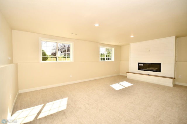 unfurnished living room featuring a fireplace, light colored carpet, and plenty of natural light