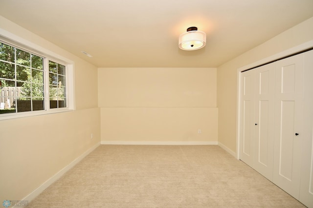 unfurnished bedroom with light carpet and a closet