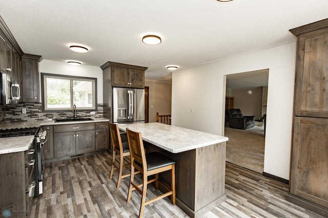 kitchen featuring a kitchen island, sink, hardwood / wood-style floors, and appliances with stainless steel finishes