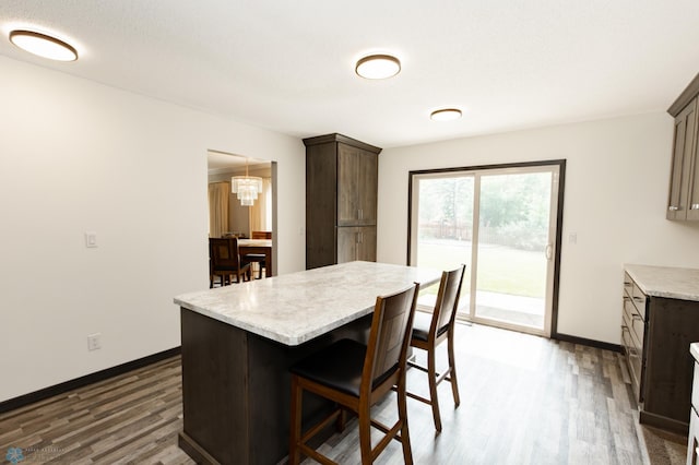 kitchen with dark brown cabinets, a kitchen island, an inviting chandelier, and dark hardwood / wood-style flooring