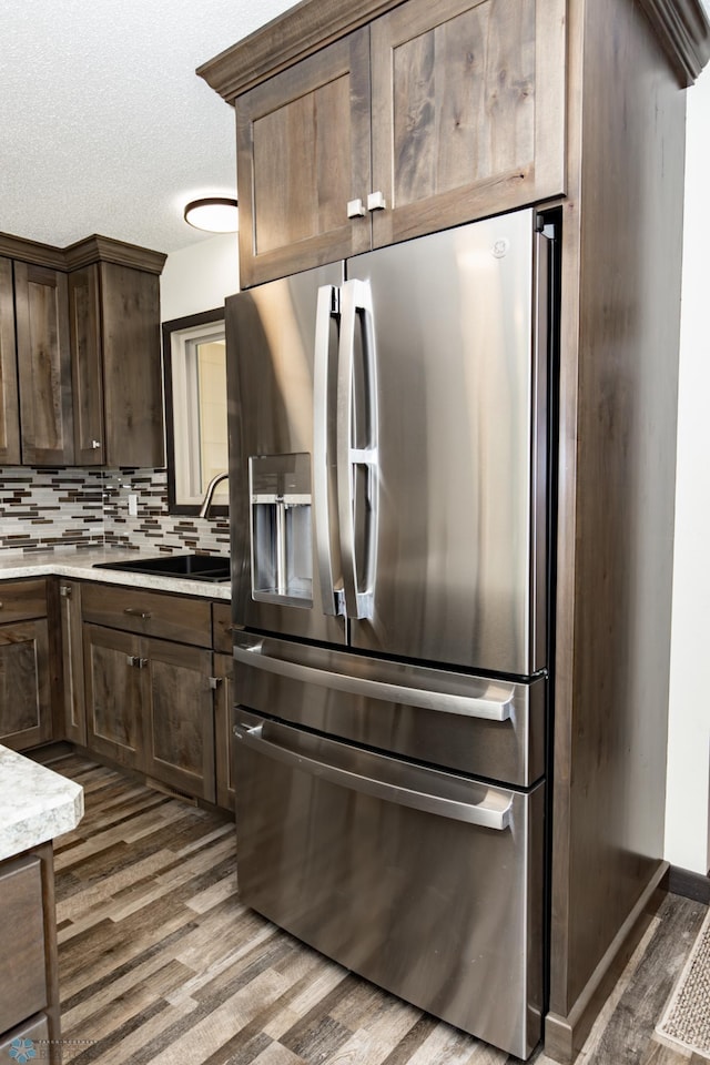 kitchen with dark brown cabinets, backsplash, sink, dark hardwood / wood-style floors, and stainless steel refrigerator with ice dispenser