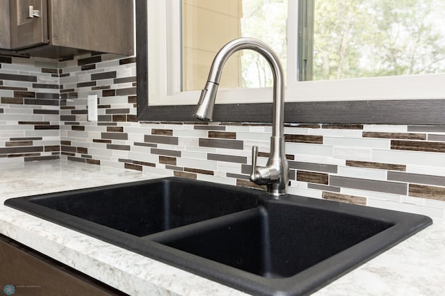 details featuring sink, dark brown cabinetry, and decorative backsplash