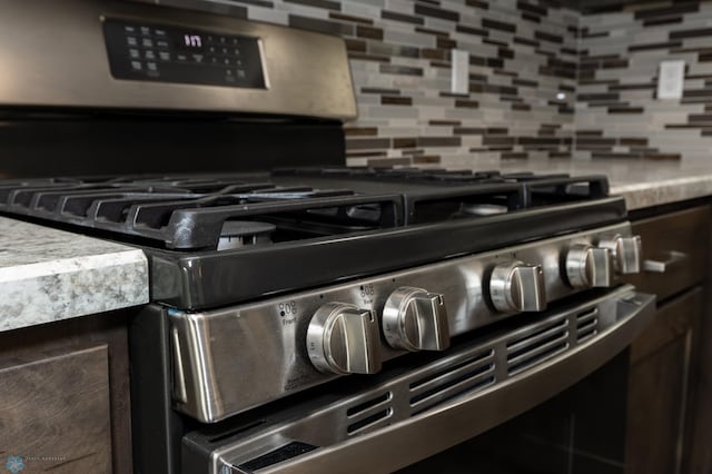 room details featuring dark brown cabinets, stainless steel gas range oven, and tasteful backsplash