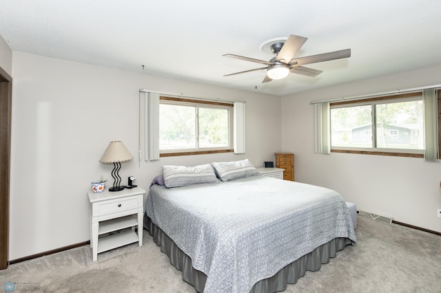 carpeted bedroom featuring multiple windows and ceiling fan