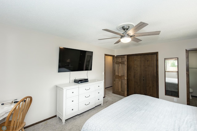 bedroom with a closet, ceiling fan, light carpet, and a textured ceiling