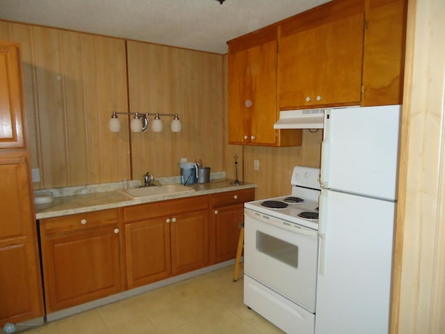 kitchen with range hood, white appliances, wood walls, and sink