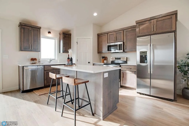 kitchen with a breakfast bar, stainless steel appliances, light hardwood / wood-style floors, and a kitchen island