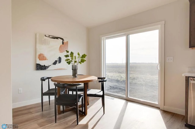 dining space with light hardwood / wood-style flooring and a water view