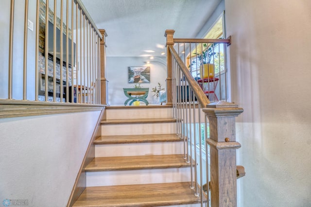 stairs featuring a textured ceiling and hardwood / wood-style floors