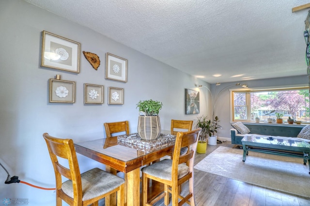 dining space featuring a textured ceiling and wood-type flooring