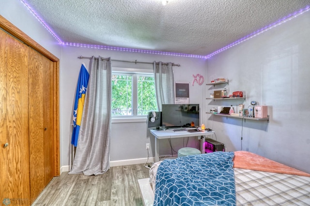 bedroom with a textured ceiling, a closet, and hardwood / wood-style flooring