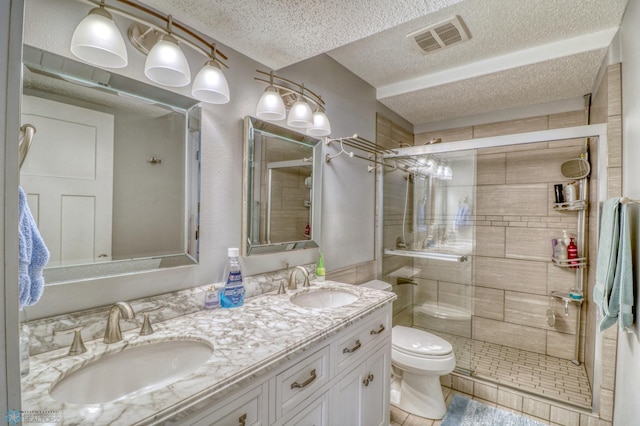 bathroom featuring vanity, a shower with shower door, toilet, and a textured ceiling