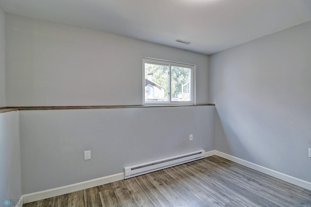 unfurnished room featuring a baseboard heating unit and light hardwood / wood-style flooring