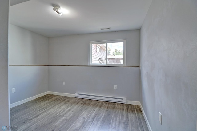 unfurnished room featuring light hardwood / wood-style flooring and a baseboard heating unit