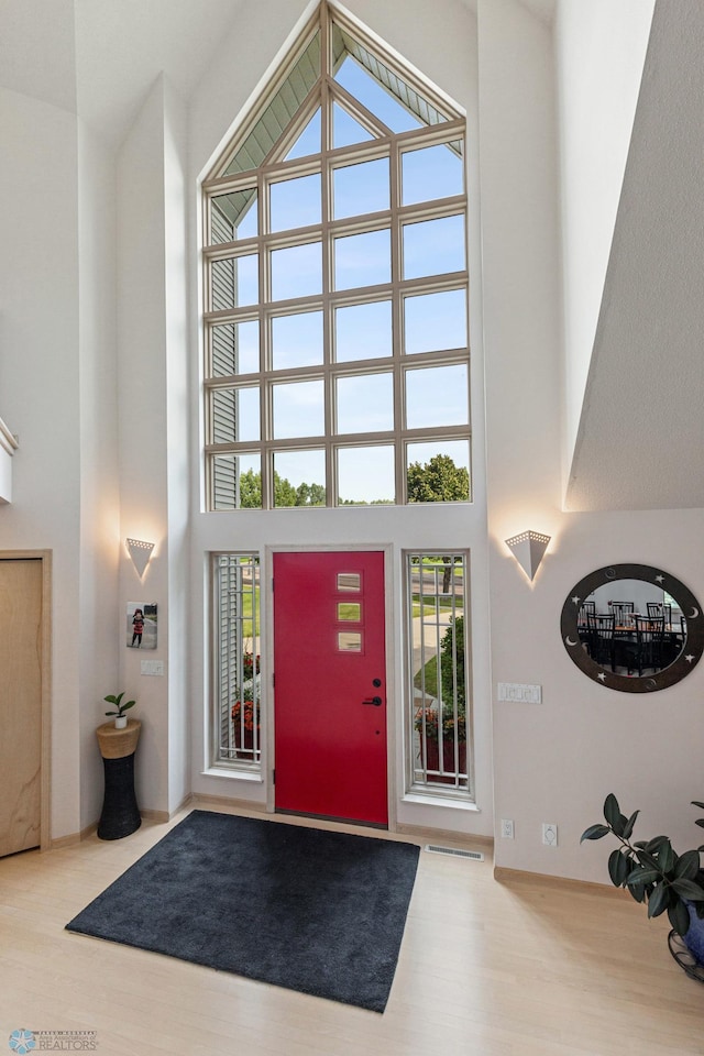 foyer with wood-type flooring and a towering ceiling