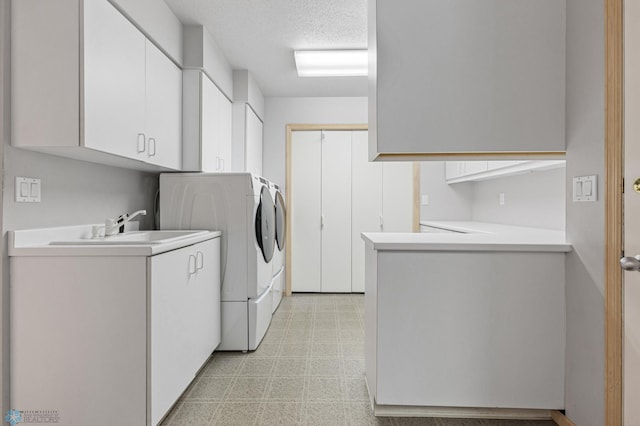 clothes washing area featuring cabinets, washer and dryer, and a textured ceiling