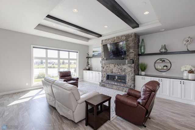 living room featuring light wood-type flooring, a fireplace, beamed ceiling, and a raised ceiling