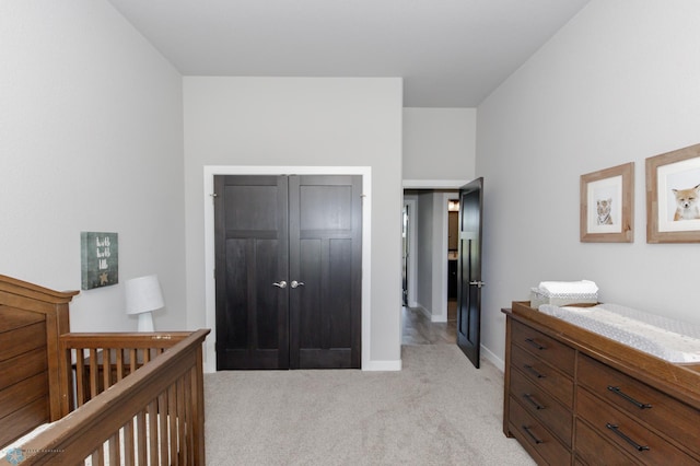 bedroom with a closet, a crib, and light carpet