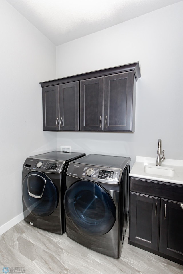 laundry area featuring washer and clothes dryer, sink, light hardwood / wood-style floors, and cabinets