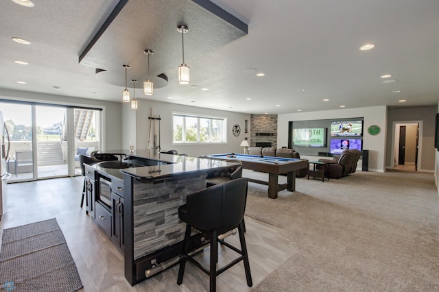 kitchen featuring pendant lighting, light colored carpet, a fireplace, and a textured ceiling