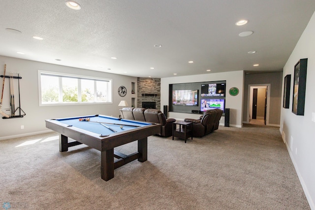 playroom featuring light carpet, pool table, a stone fireplace, and a textured ceiling