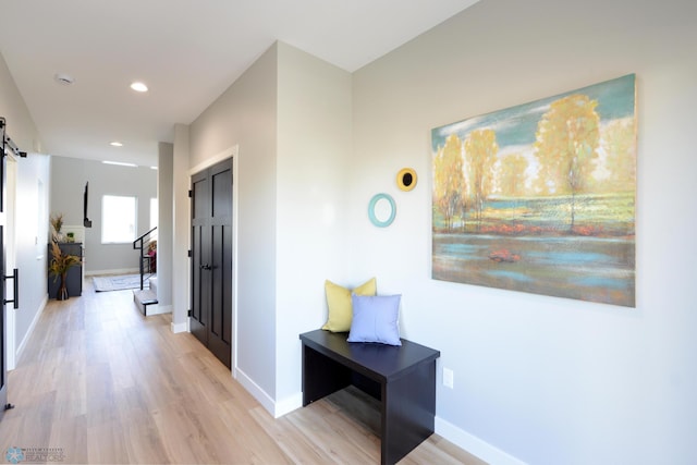 corridor featuring a barn door and light hardwood / wood-style flooring