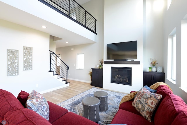 living room featuring light wood-type flooring and a towering ceiling