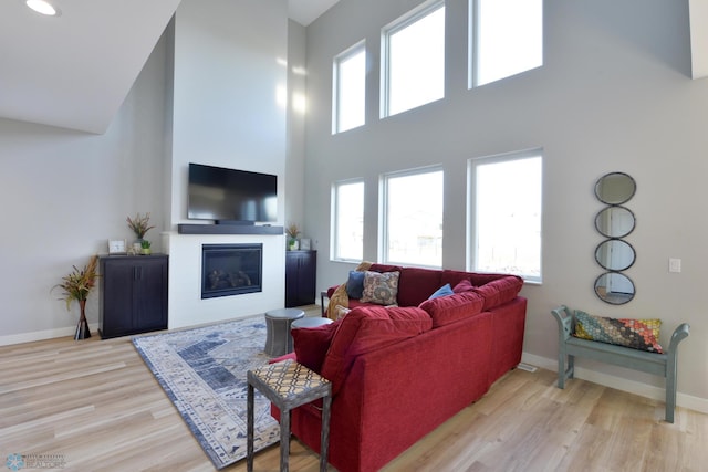 living room with light wood-type flooring and a towering ceiling