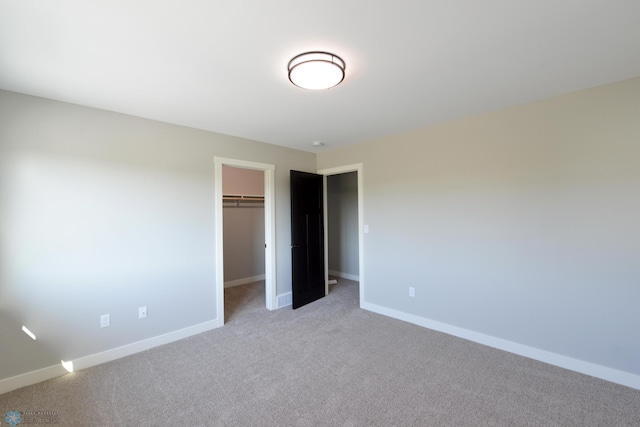 unfurnished bedroom featuring light carpet, a closet, and a spacious closet