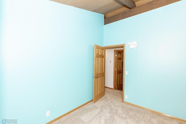 unfurnished room with wood ceiling, light colored carpet, and beamed ceiling