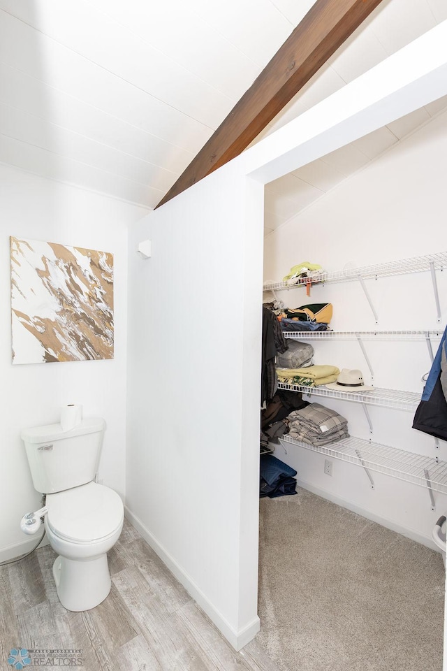 bathroom featuring lofted ceiling with beams, hardwood / wood-style floors, and toilet