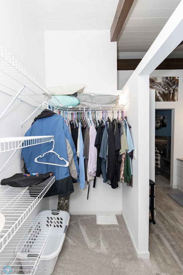 spacious closet with beam ceiling and hardwood / wood-style flooring