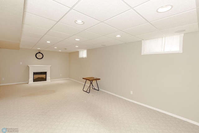 basement with a paneled ceiling and carpet flooring