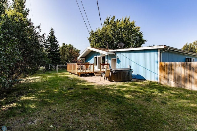 back of property with a deck, a yard, and a hot tub