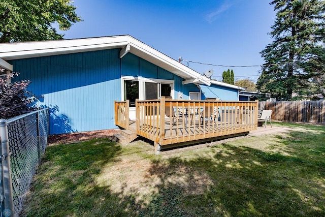 rear view of house with a wooden deck and a yard