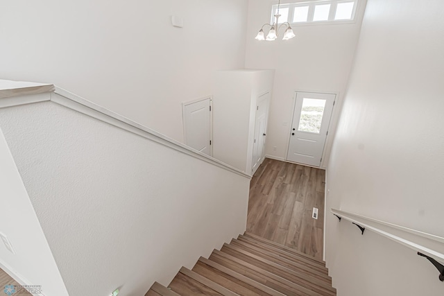 staircase featuring a high ceiling, a chandelier, and hardwood / wood-style flooring