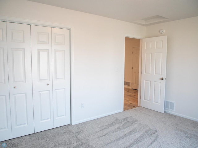 unfurnished bedroom with a closet and light colored carpet